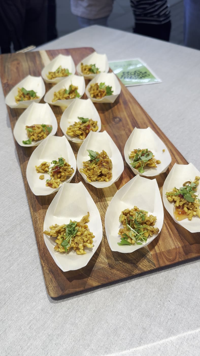 Small paper boats of Sloppy Jo's plant-based filling arranged on a wooden board at a tasting event - what the "plate your own" format looks like when served
